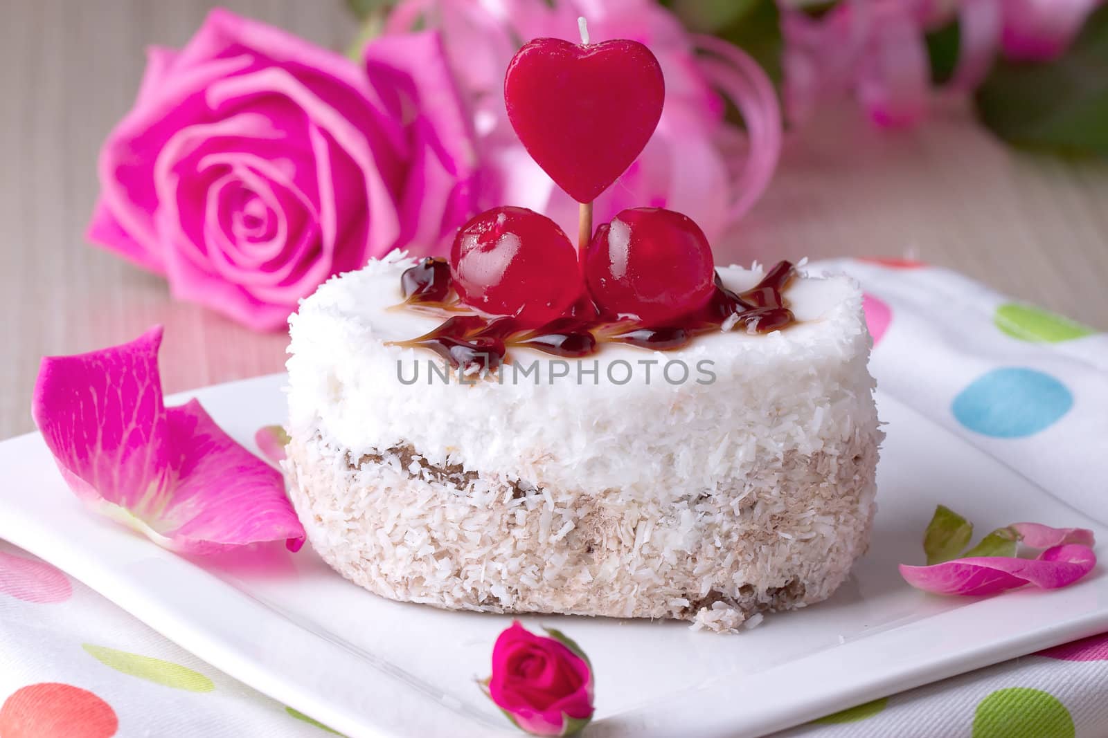 Celebratory cake with cherries on a background of pink roses