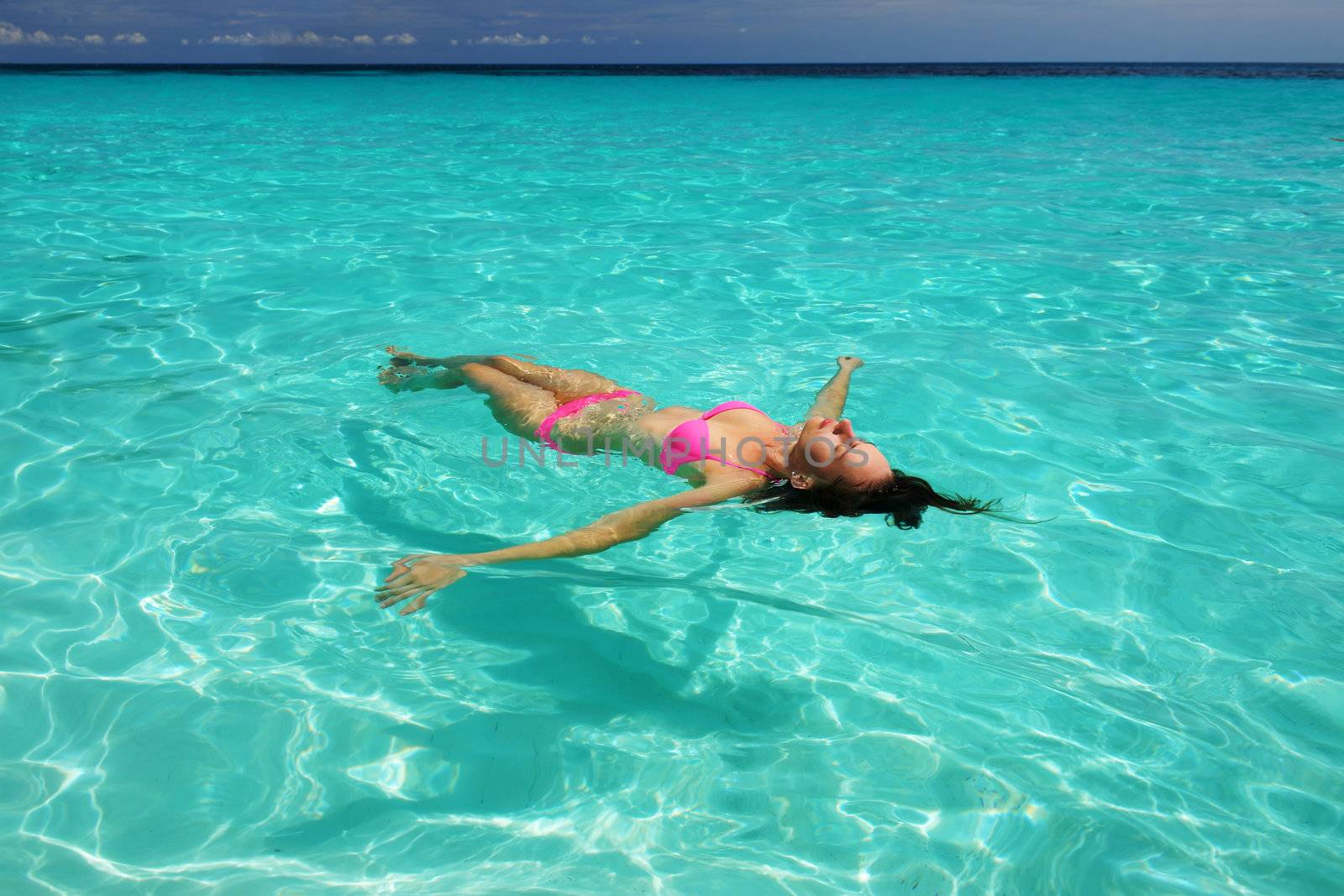 Woman in bikini lying on water  by haveseen