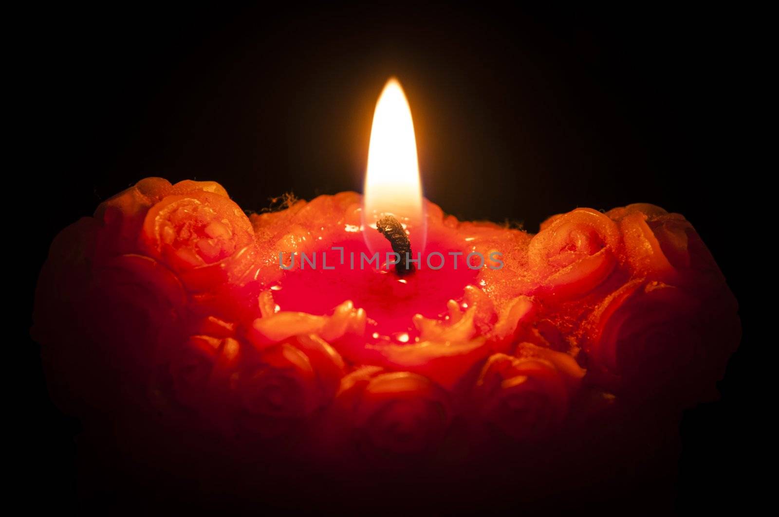 An image of red candle with flame on black background