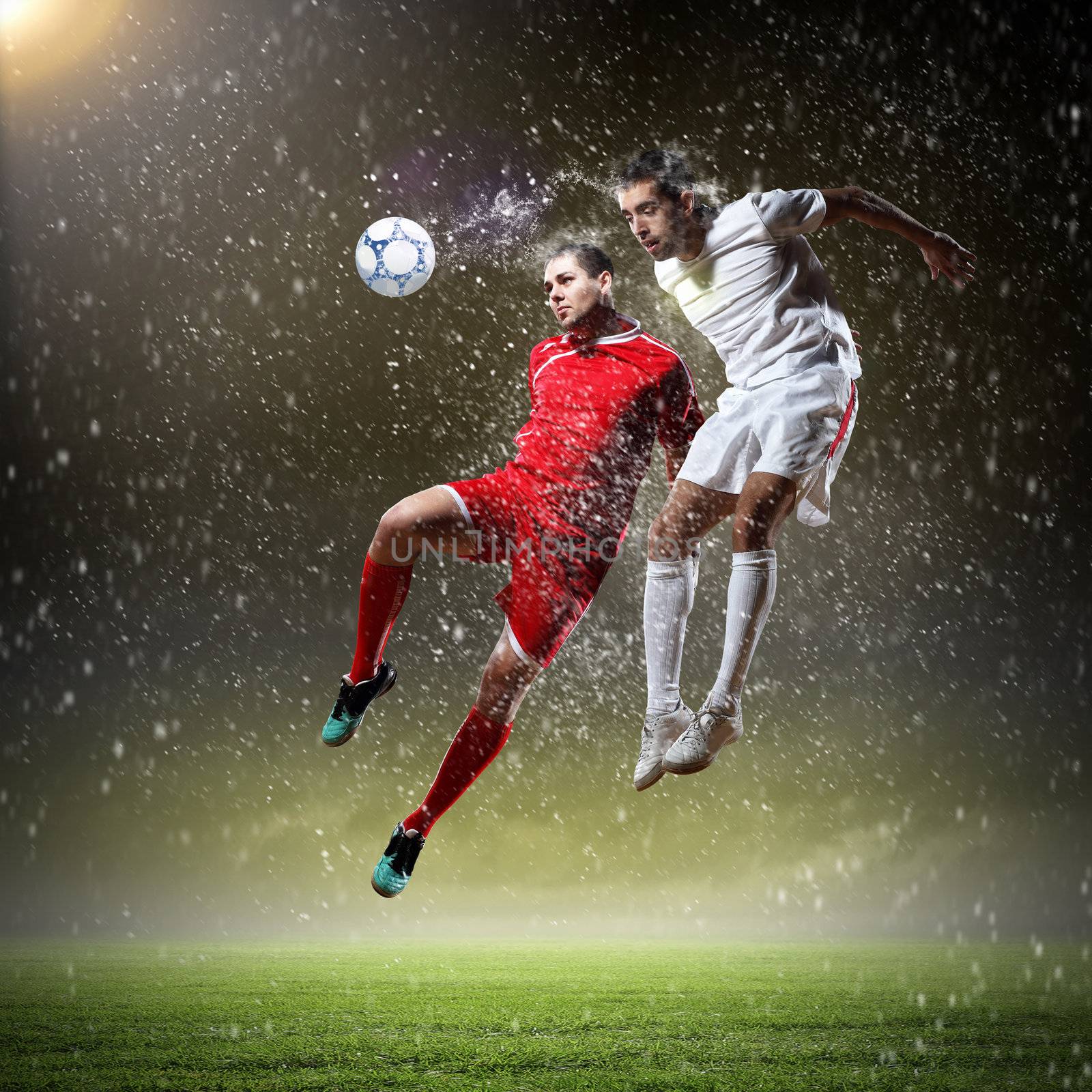 two football players in jump to strike the ball at the stadium