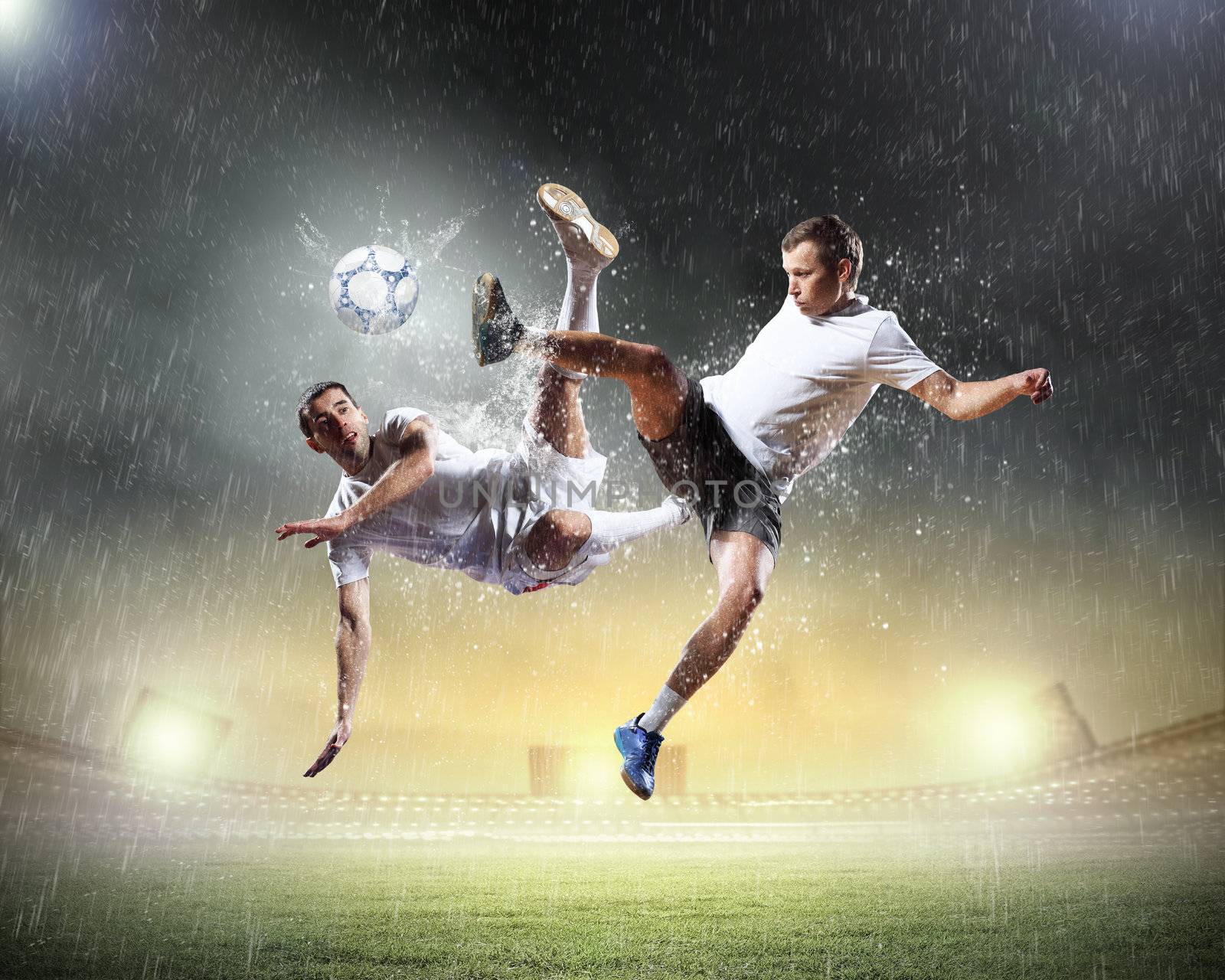 two football players in jump to strike the ball at the stadium