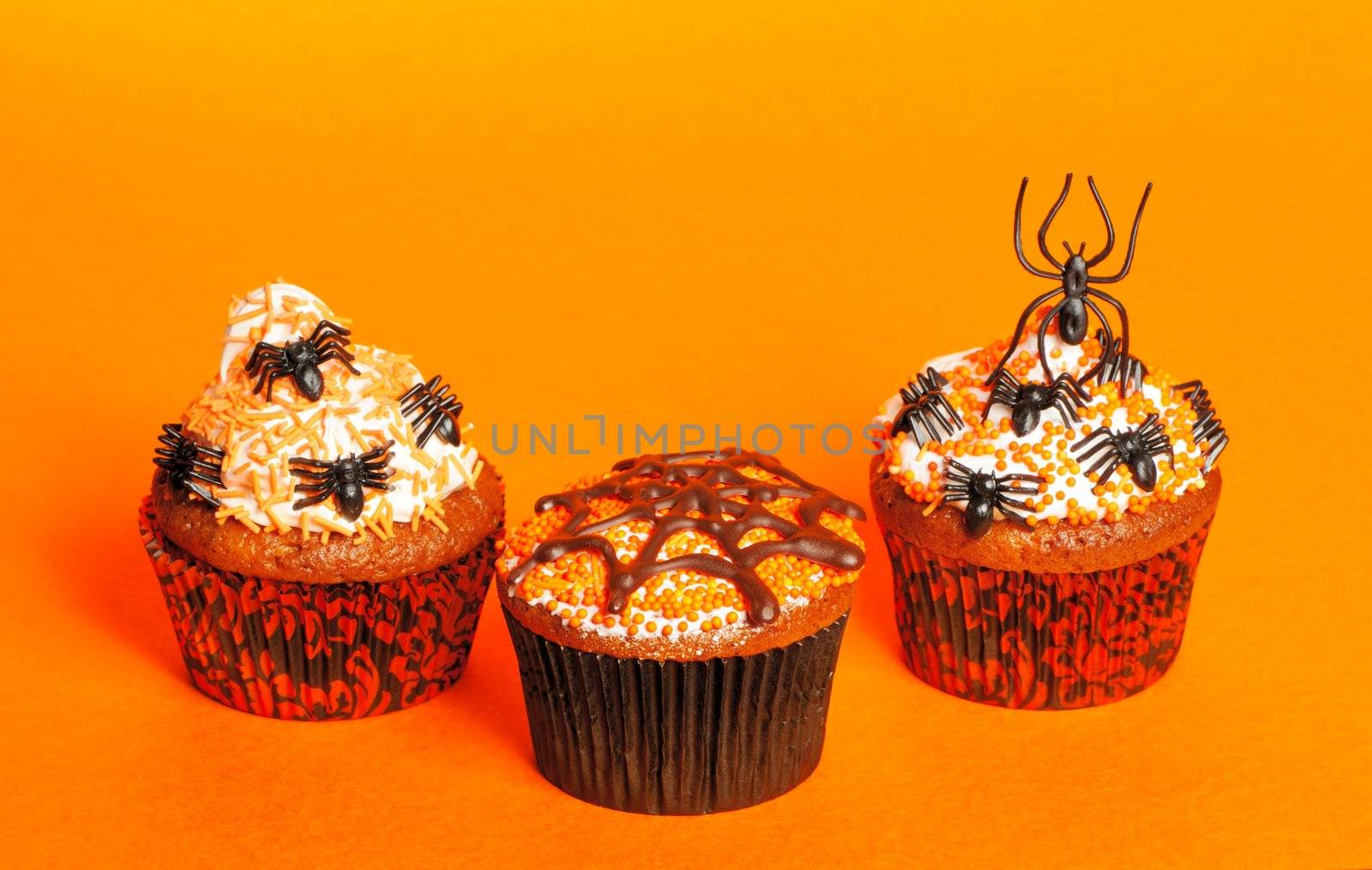 Halloween cupcakes with decoration over orange background