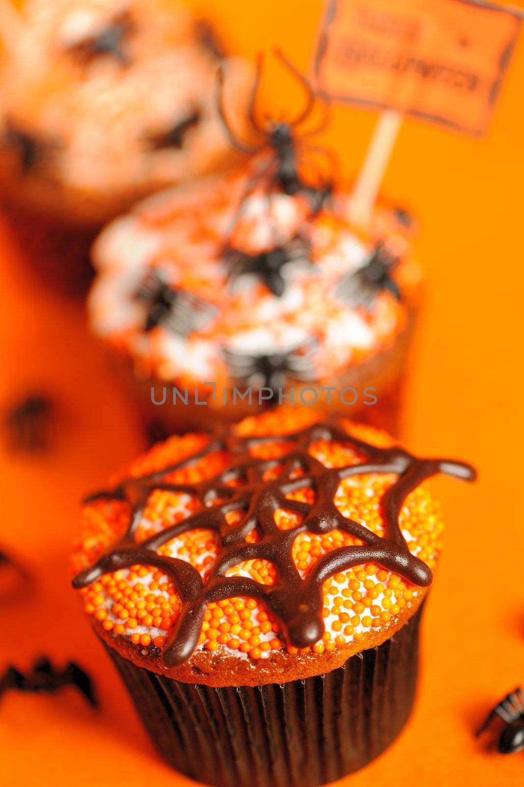 Halloween cupcakes with decoration over orange background