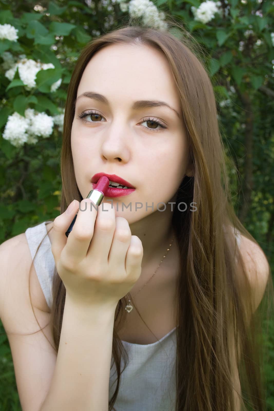 Sensual young woman applying cosmetics on her lips