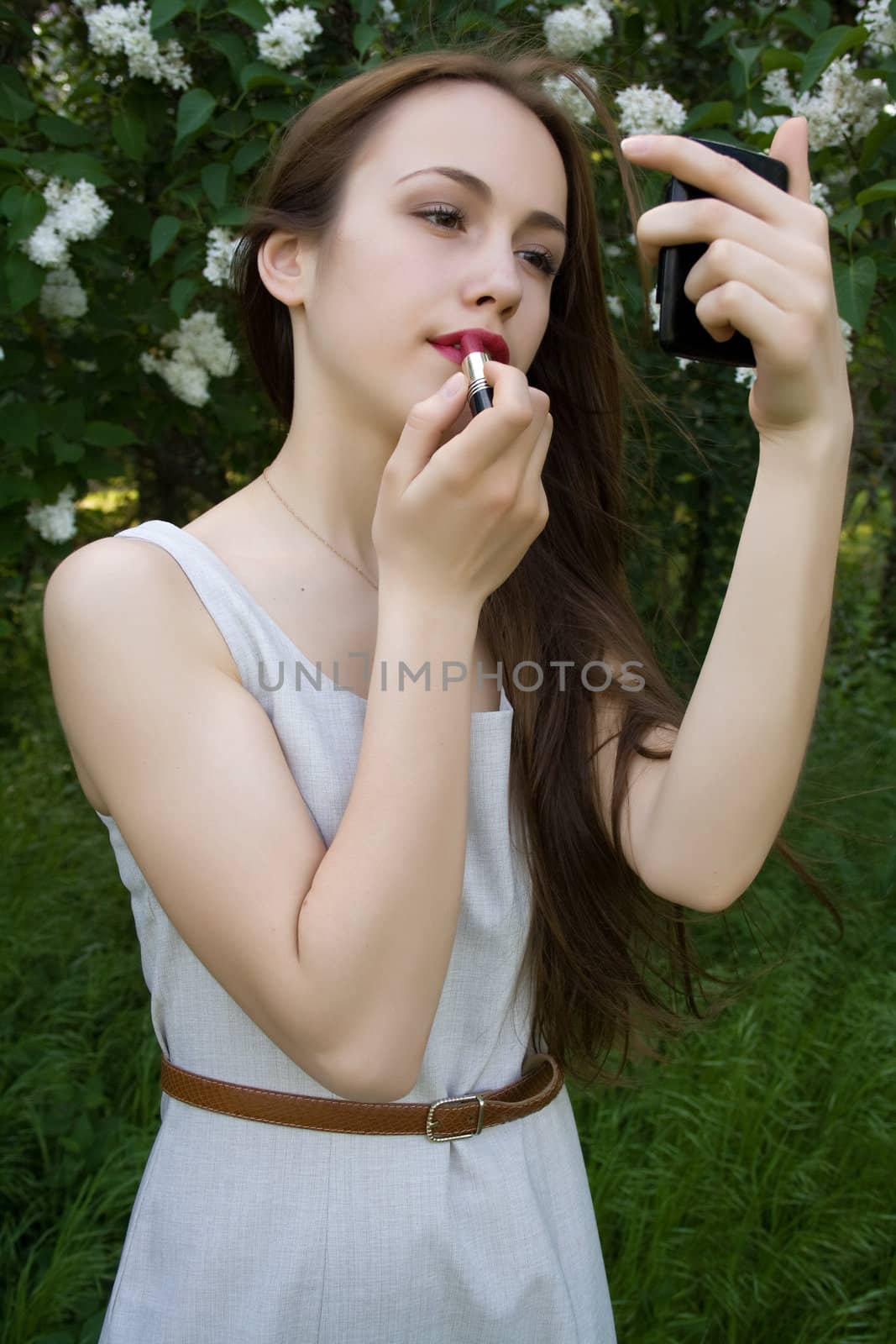 Girl applying lipstick on the lips