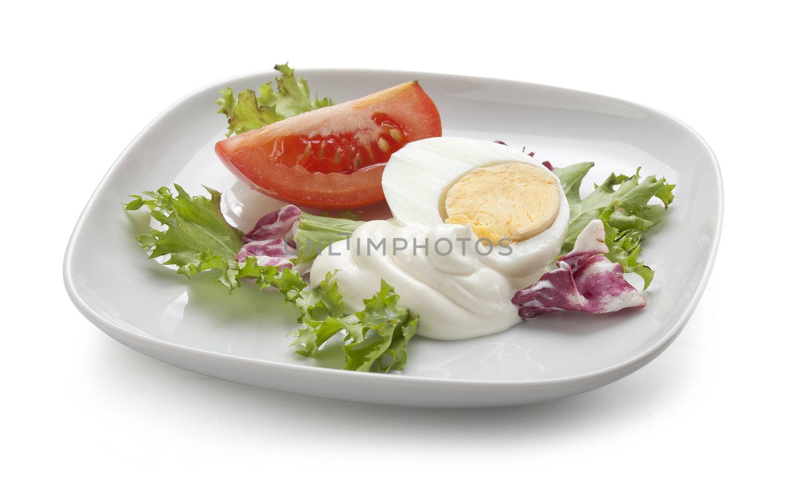 Piece of tomat, boiled egg and lettuce with mayonnaise on the white plate