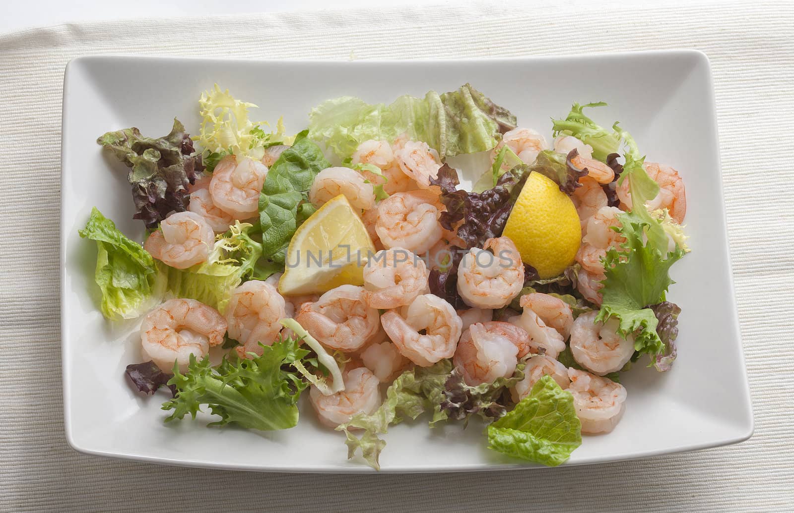 Boiled shrimp's tails with lemon and lettuce on the white plate