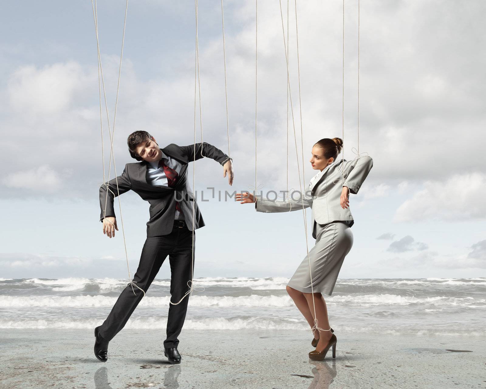 Image of businesspeople hanging on strings like marionettes against sea background. Conceptual photography