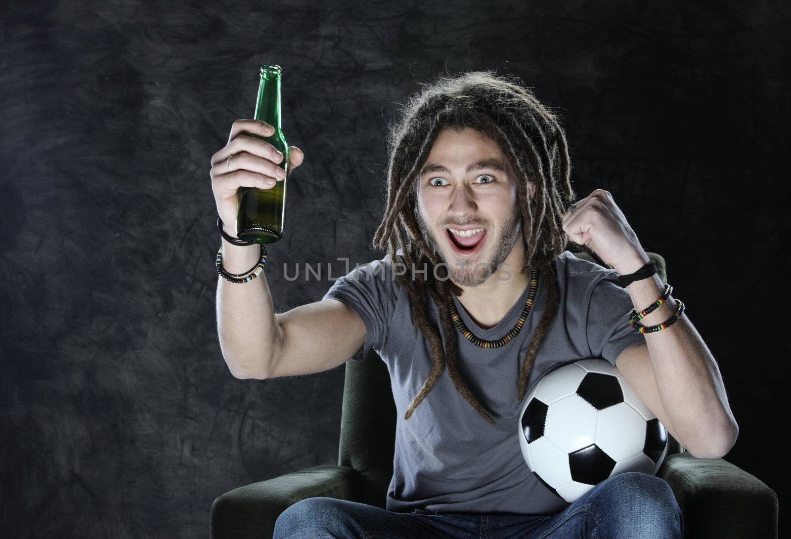 Young adult man exults watching football on television: Goal!