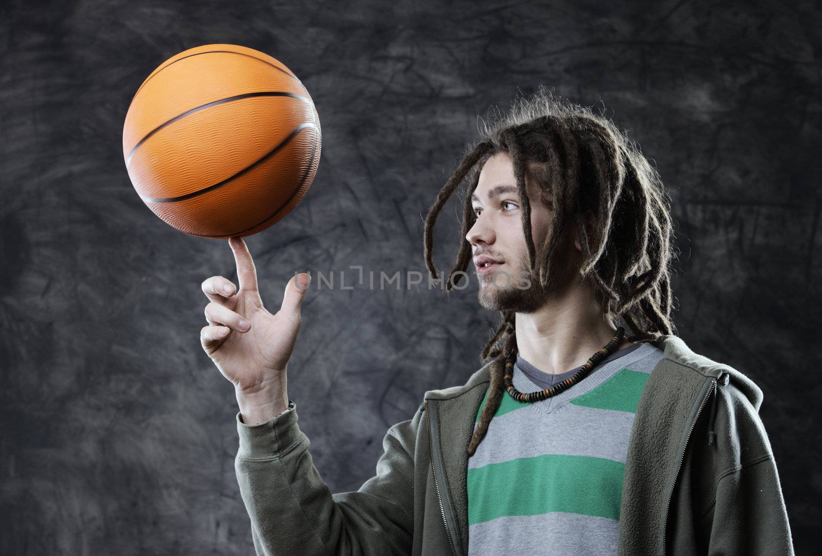 Portrait of young man spinning basketball on finger