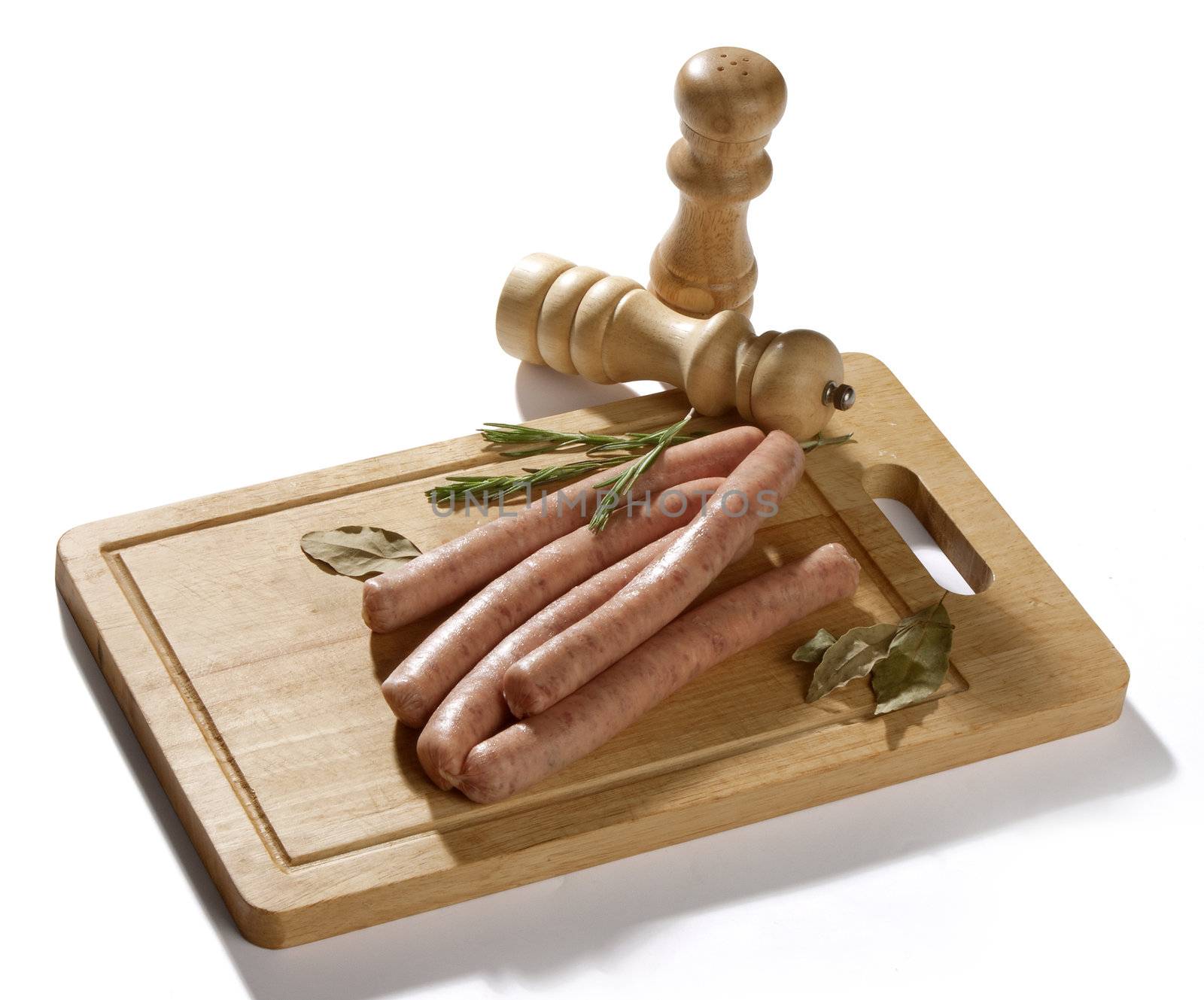 Some raw bavarian sausages on the wooden board with rosemary and bay leaf