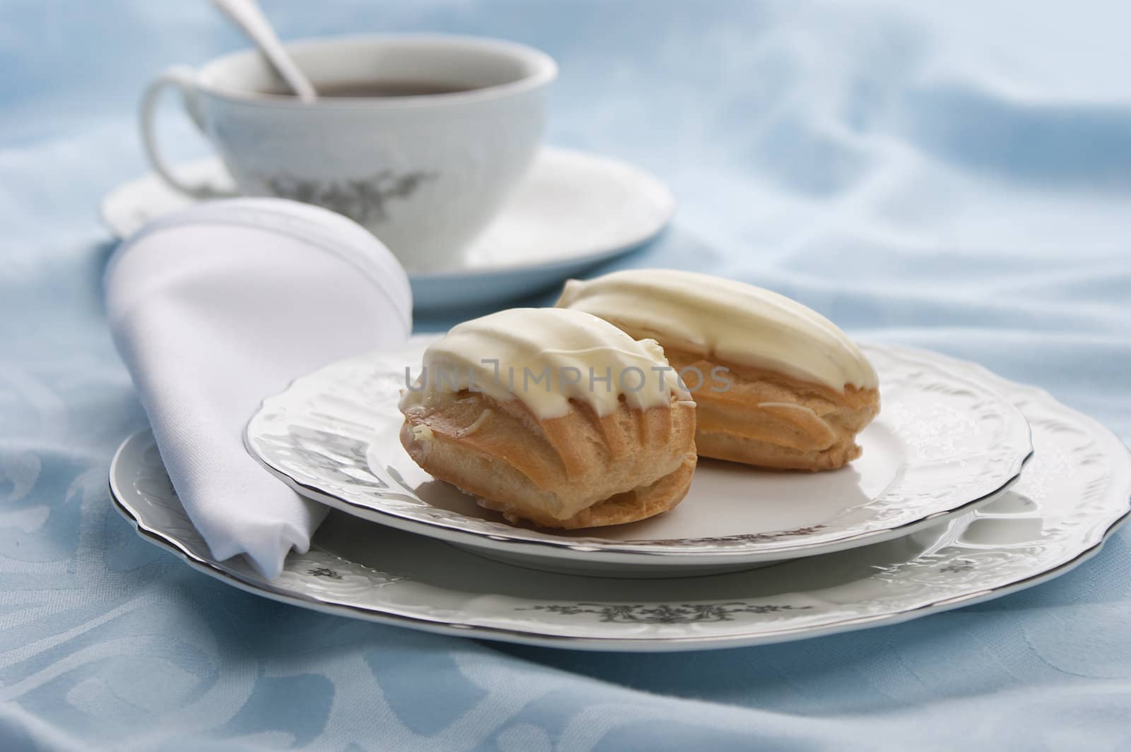 Two cream-filled French pastry on the plate with tea