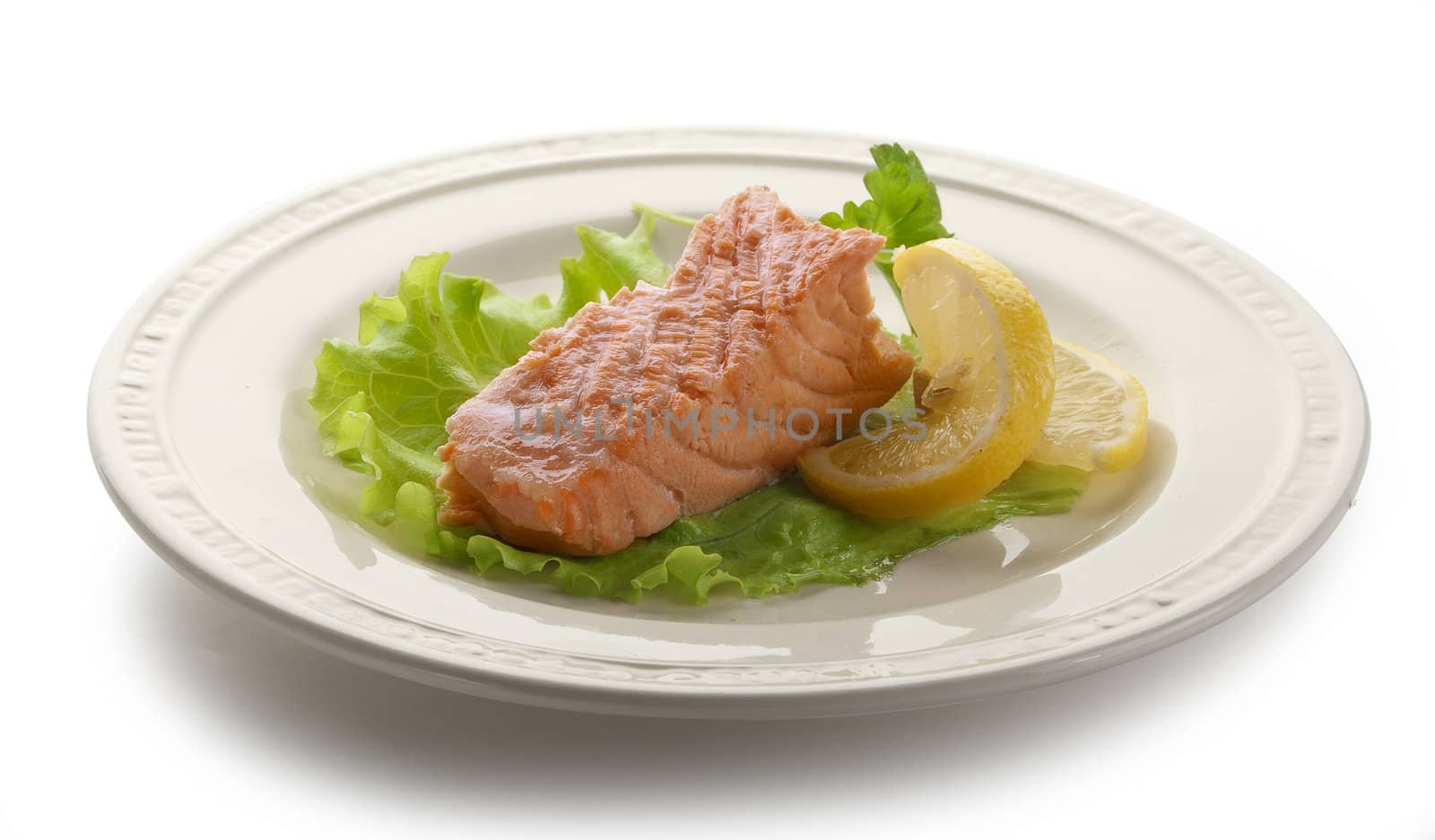 Piece of steamed salmon with lemon and lettuce on the white plate