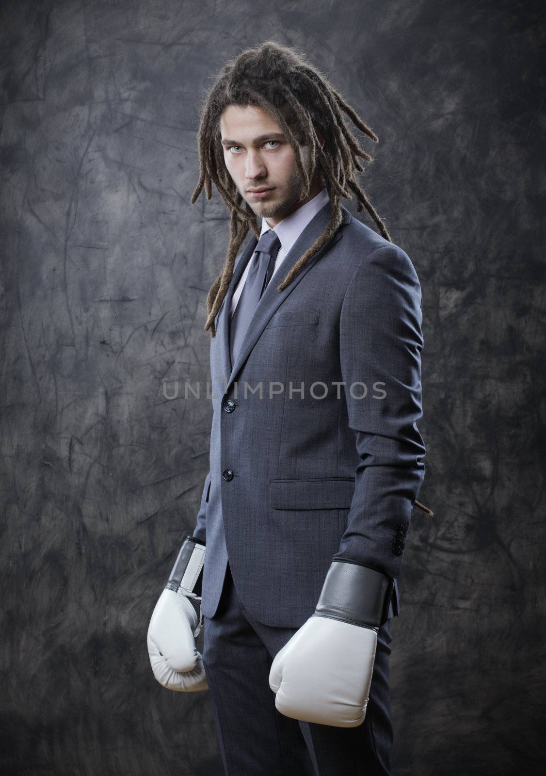 Portrait of a young business man wearing boxing gloves against grunge background