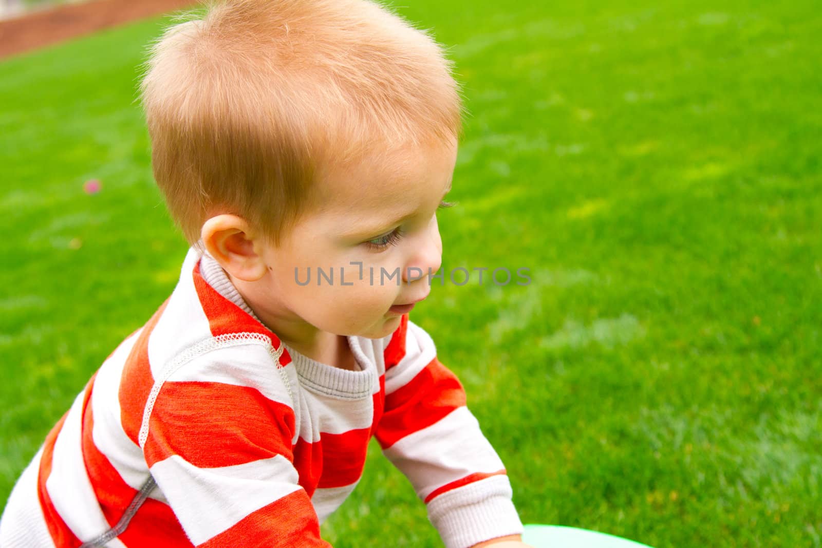 A portrait of a young boy playing outdoors wearing a red and white striped shirt.