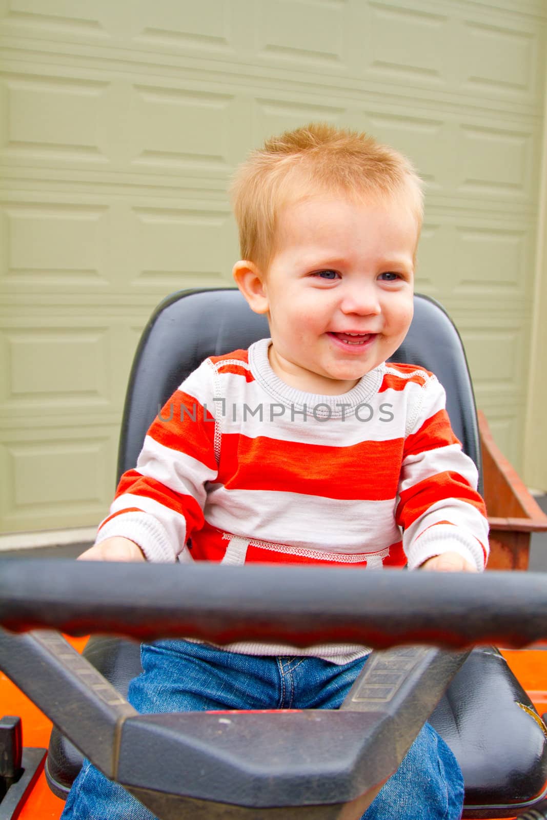 A portrait of a young boy playing outdoors wearing a red and white striped shirt.