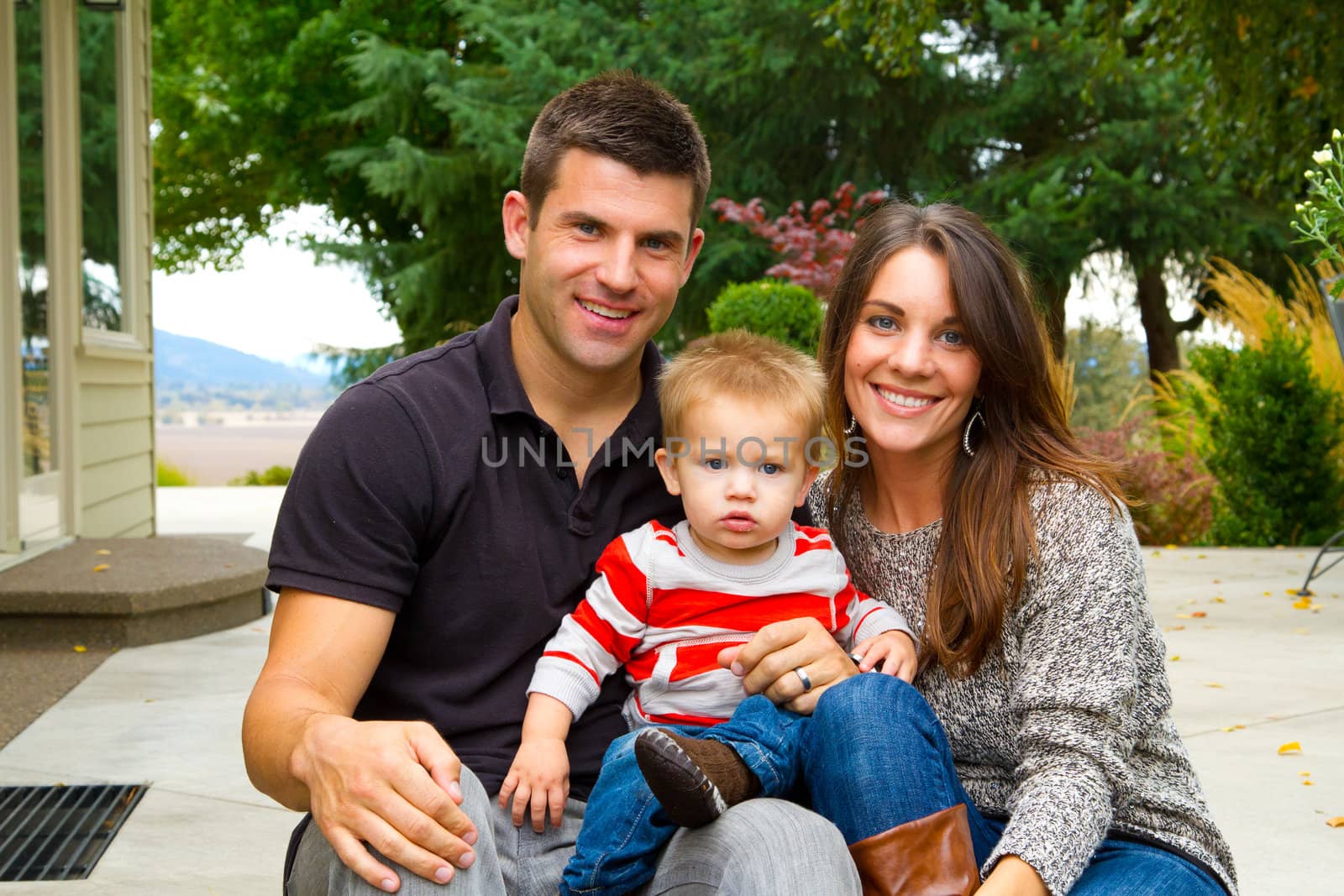 A husband and wife have their first child and pose for a portrait with the boy.