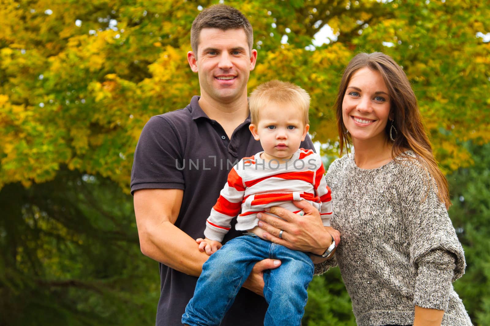 A husband and wife have their first child and pose for a portrait with the boy.