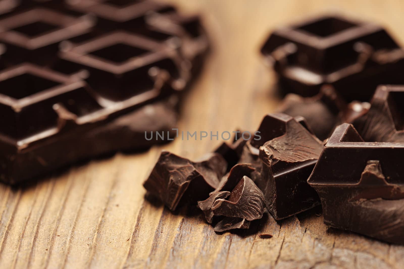 Pieces of dark chocolate  on a wooden background by stokkete