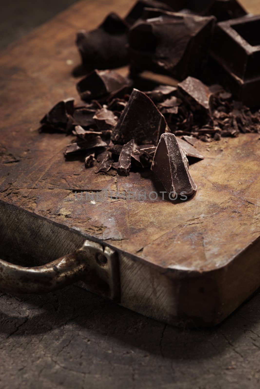 Pieces of dark chocolate  on a wooden background by stokkete
