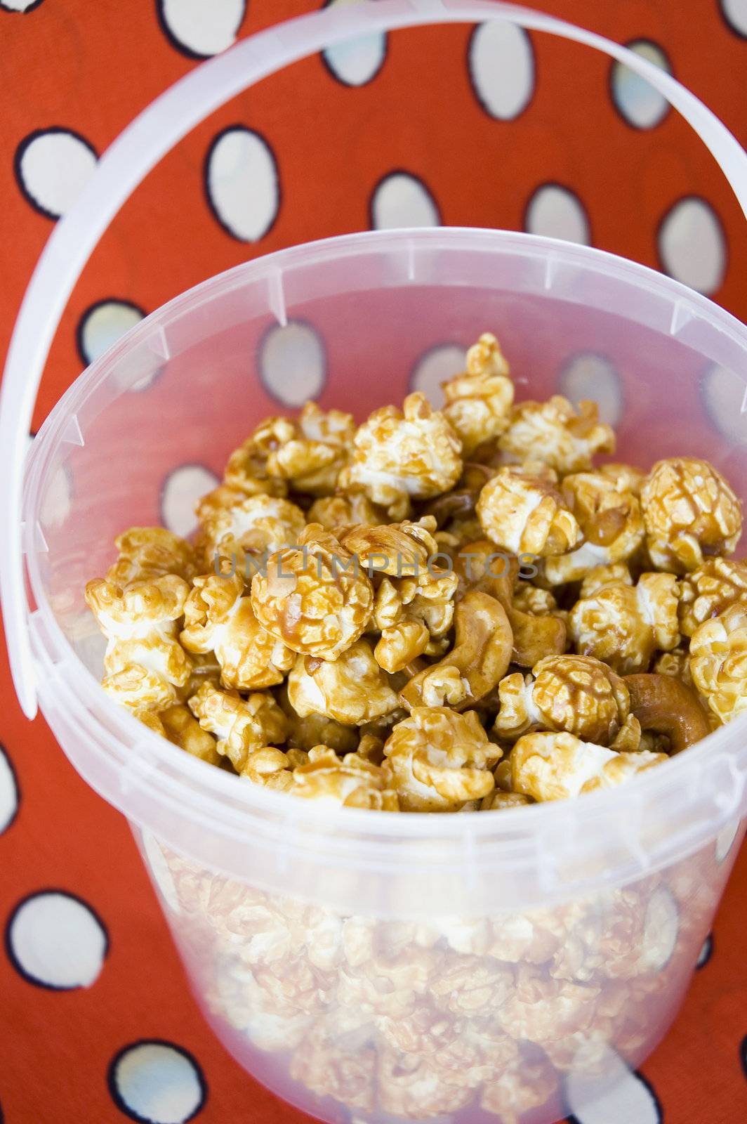 close up caramel popcorn in bucket with red background