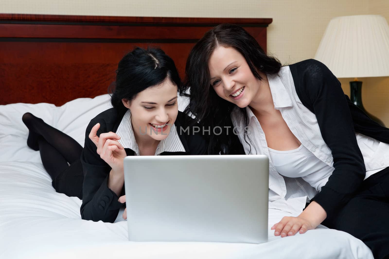 Two happy female executives working on laptop