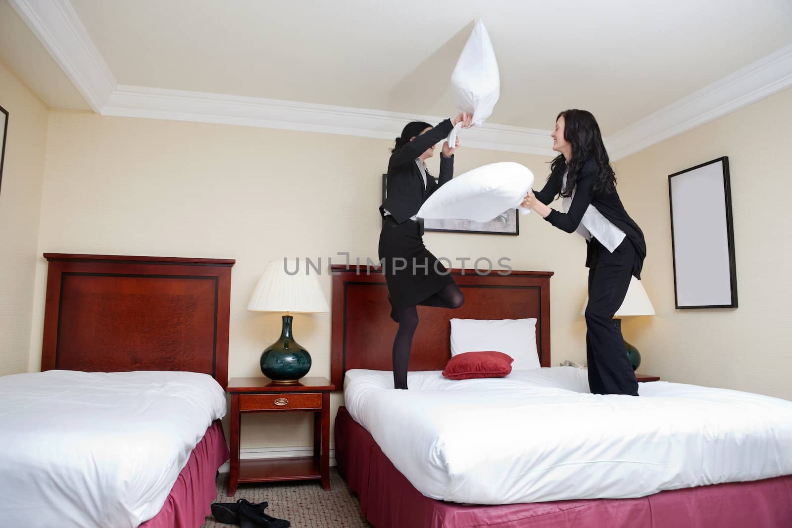 Two female executives having pillow fight in hotel room