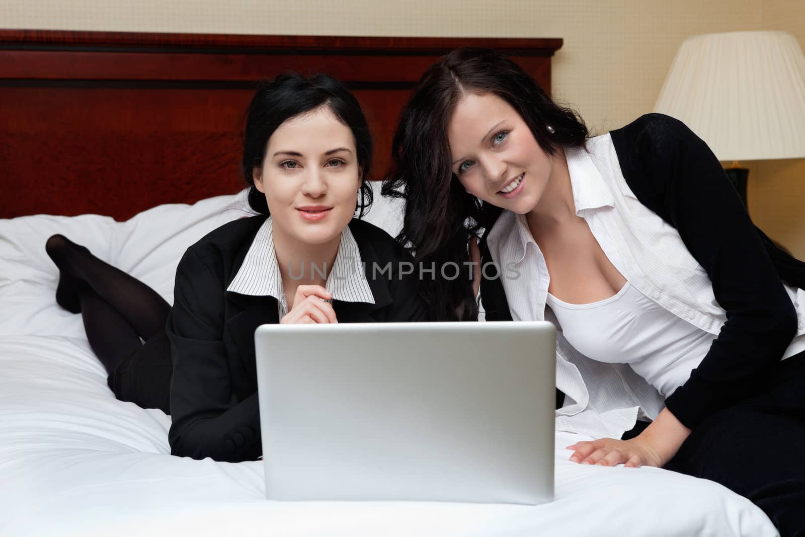 Portrait of two happy female executives working on laptop