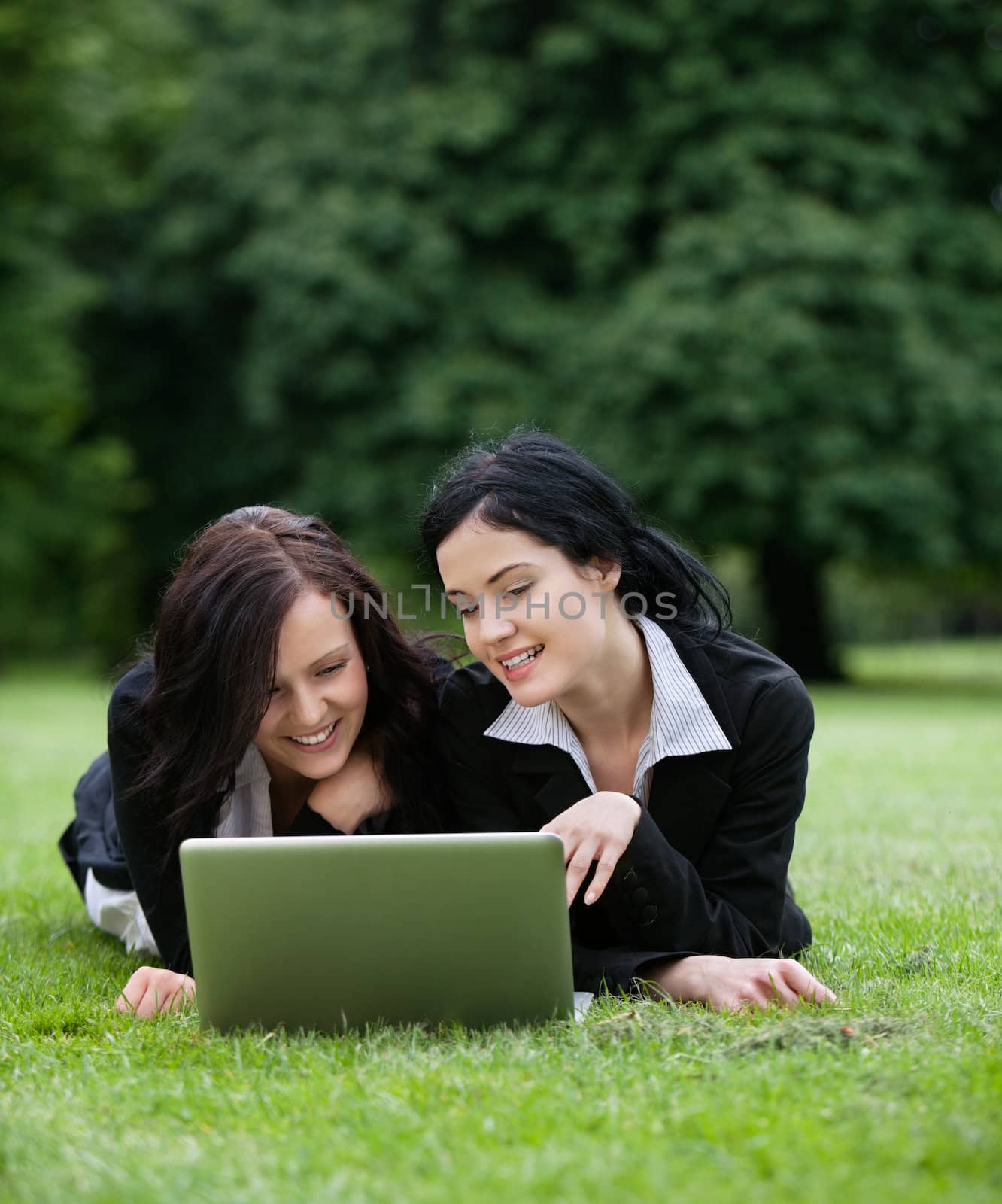 Two young business stuents in park with laptop