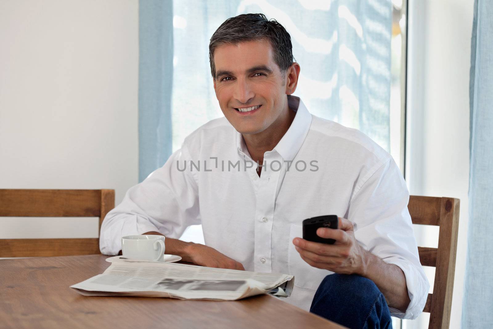 Man Reading Morning Newspaper and Checking Phone