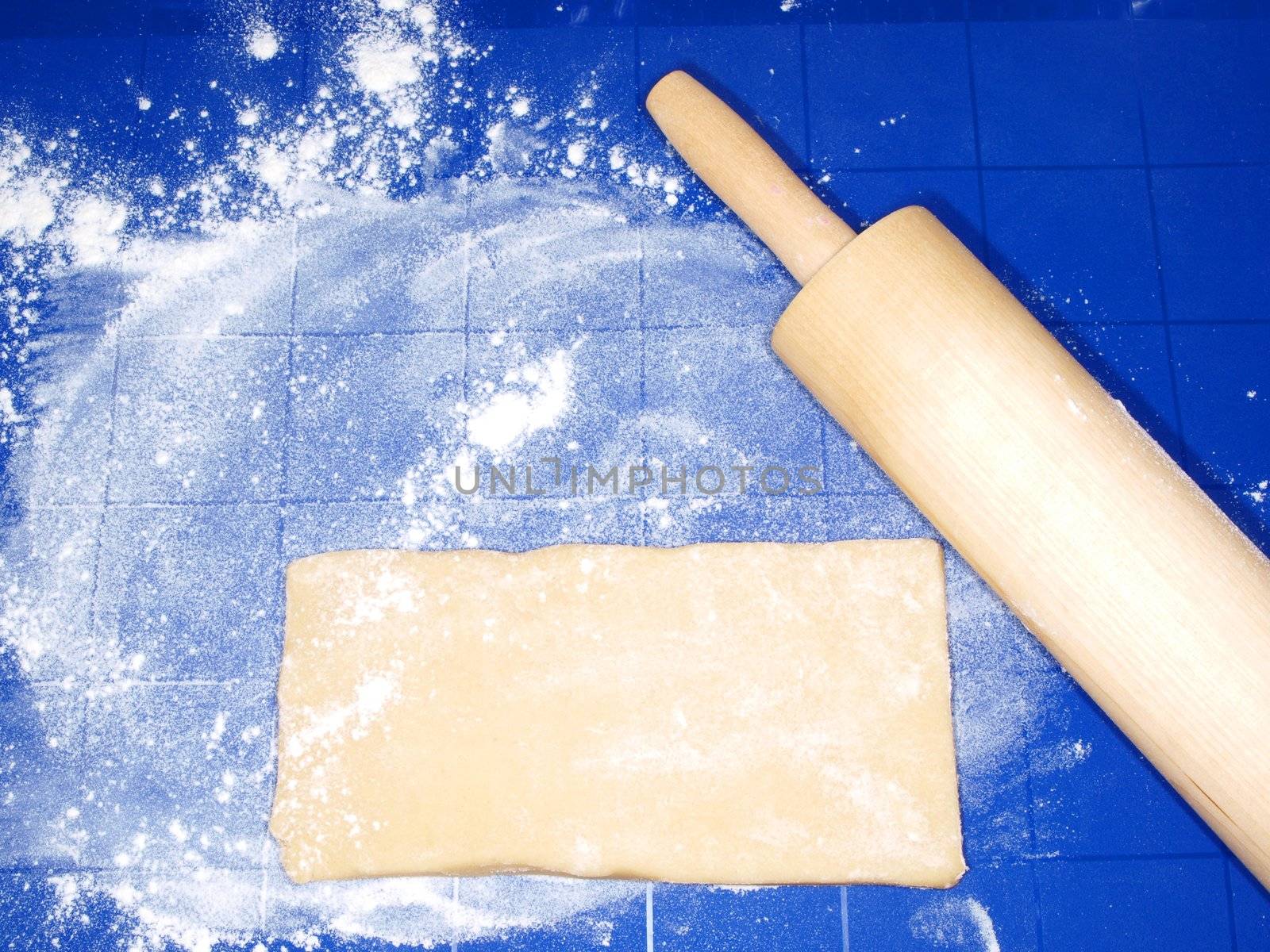 Dough on blue silicon mat, with wooden pin