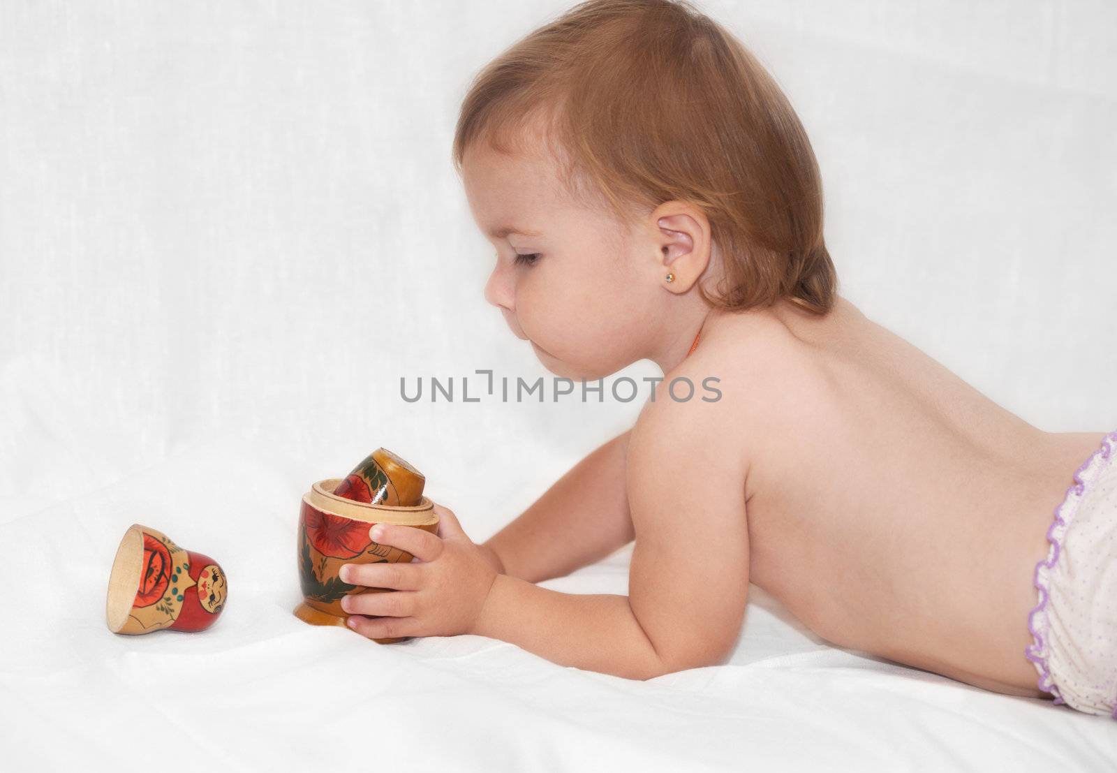 The beautiful baby plays by a toy a bed