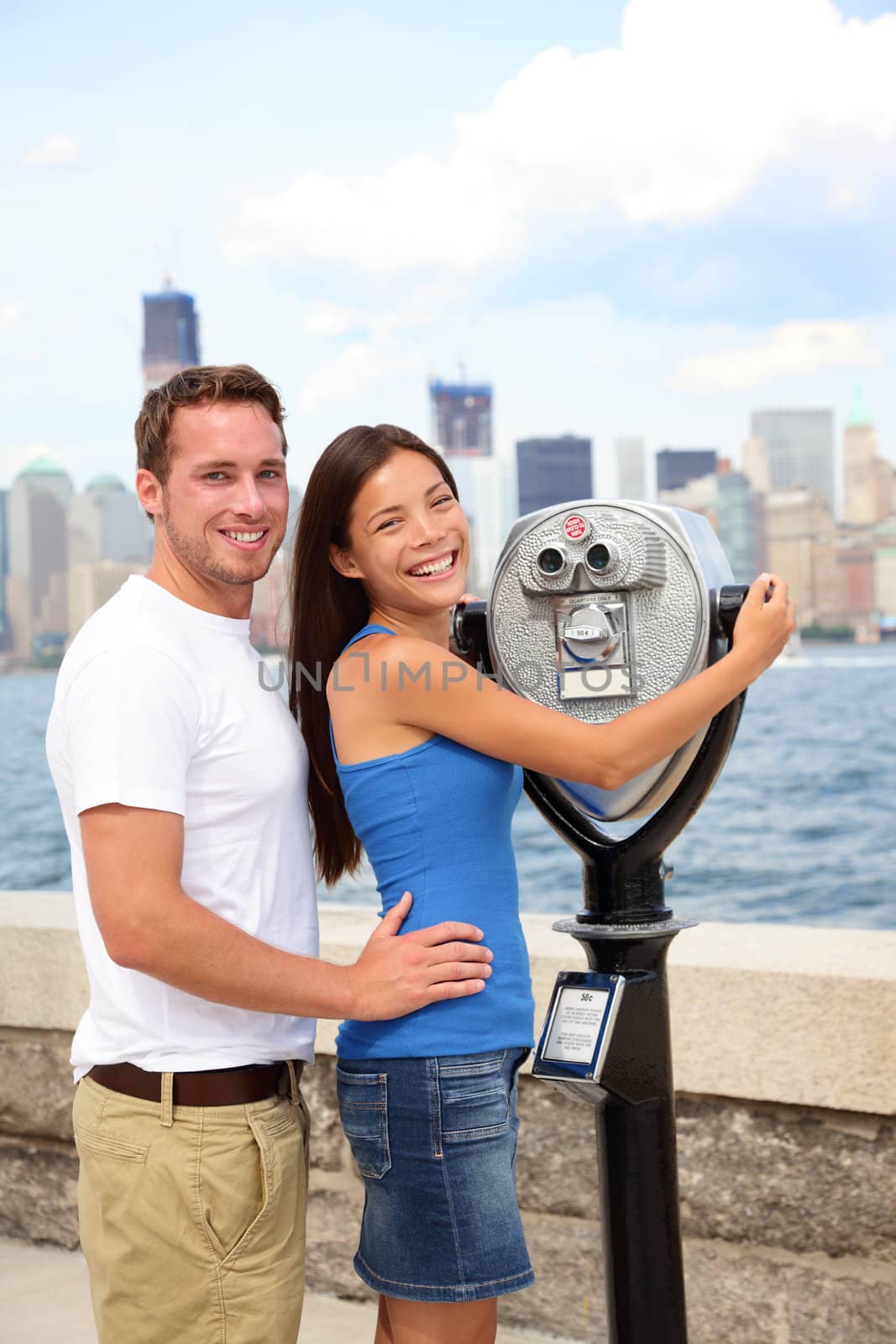 Tourists Couple - Tourism New York, USA. Happy romantic dating interracial couple sightseeing looking at Manhattan and New York City skyline from Ellis Island. Asian woman, Caucasian man.