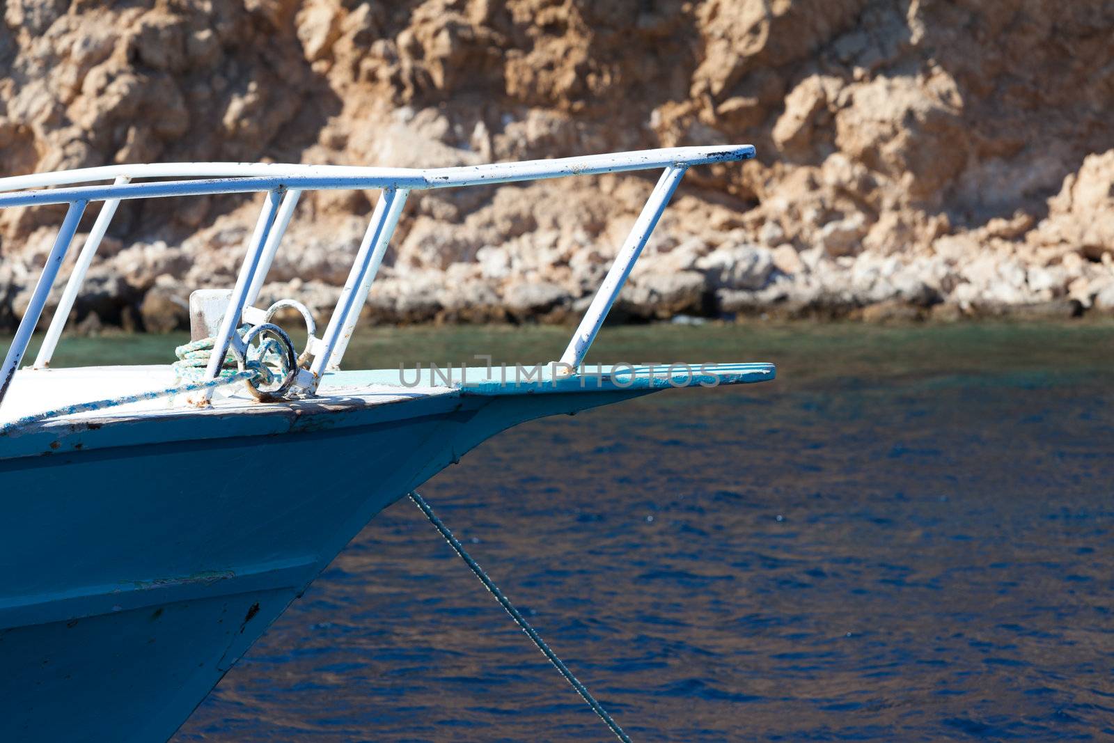 Front bow of a yacht moored with a rock face in the background.