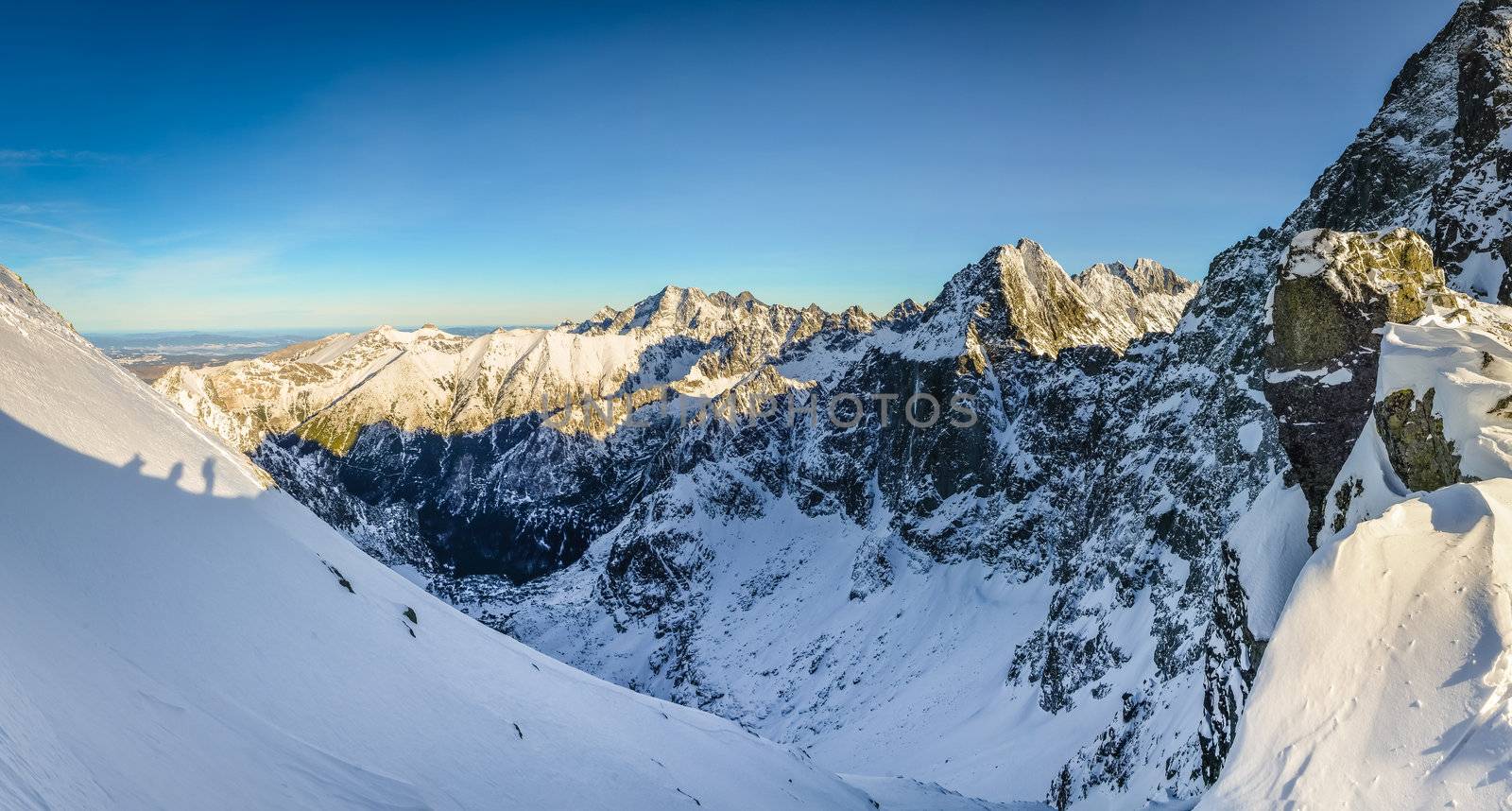 Winter mountains and shadow silhouette of people trekking by martinm303