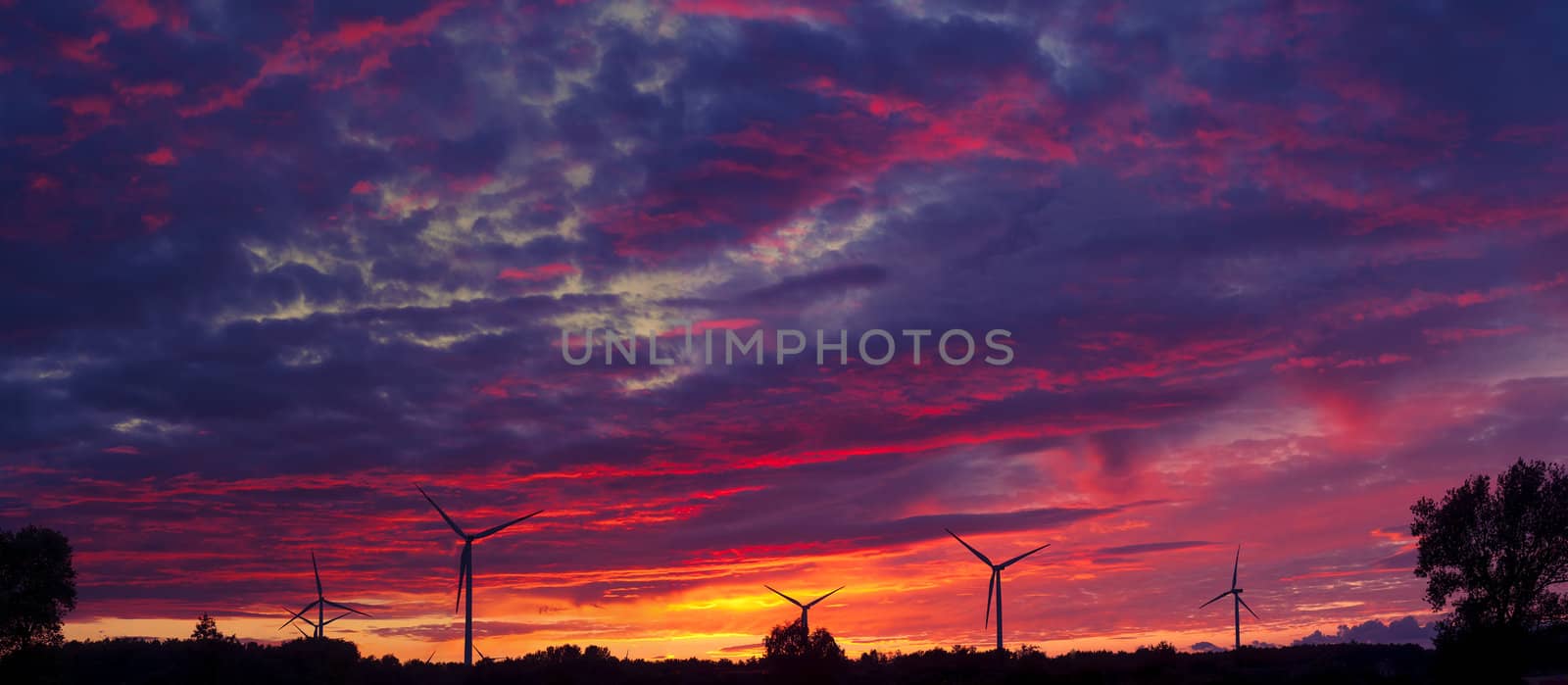 A silhouette of windturbines on a amazing sunset