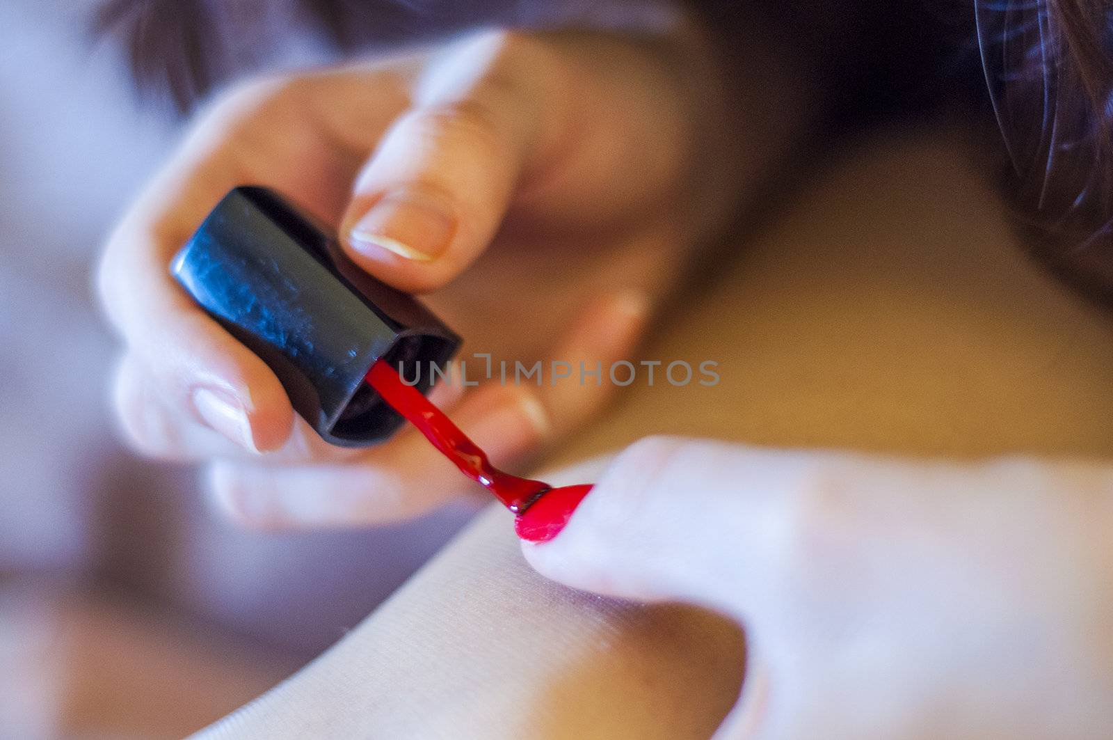 Girl paints her nail into red color. Shallow DOF