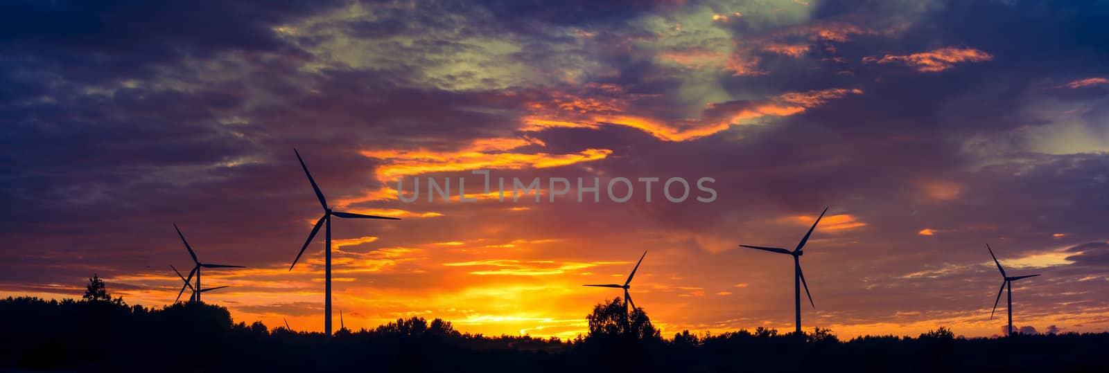 A silhouette of windturbines on a amazing sunset