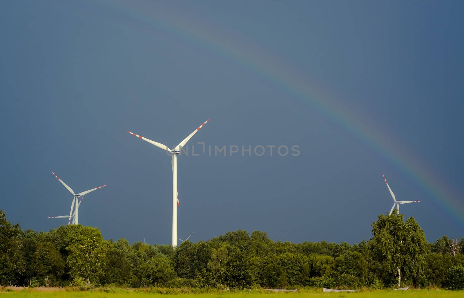 Windturbines against blue sky and rainbow