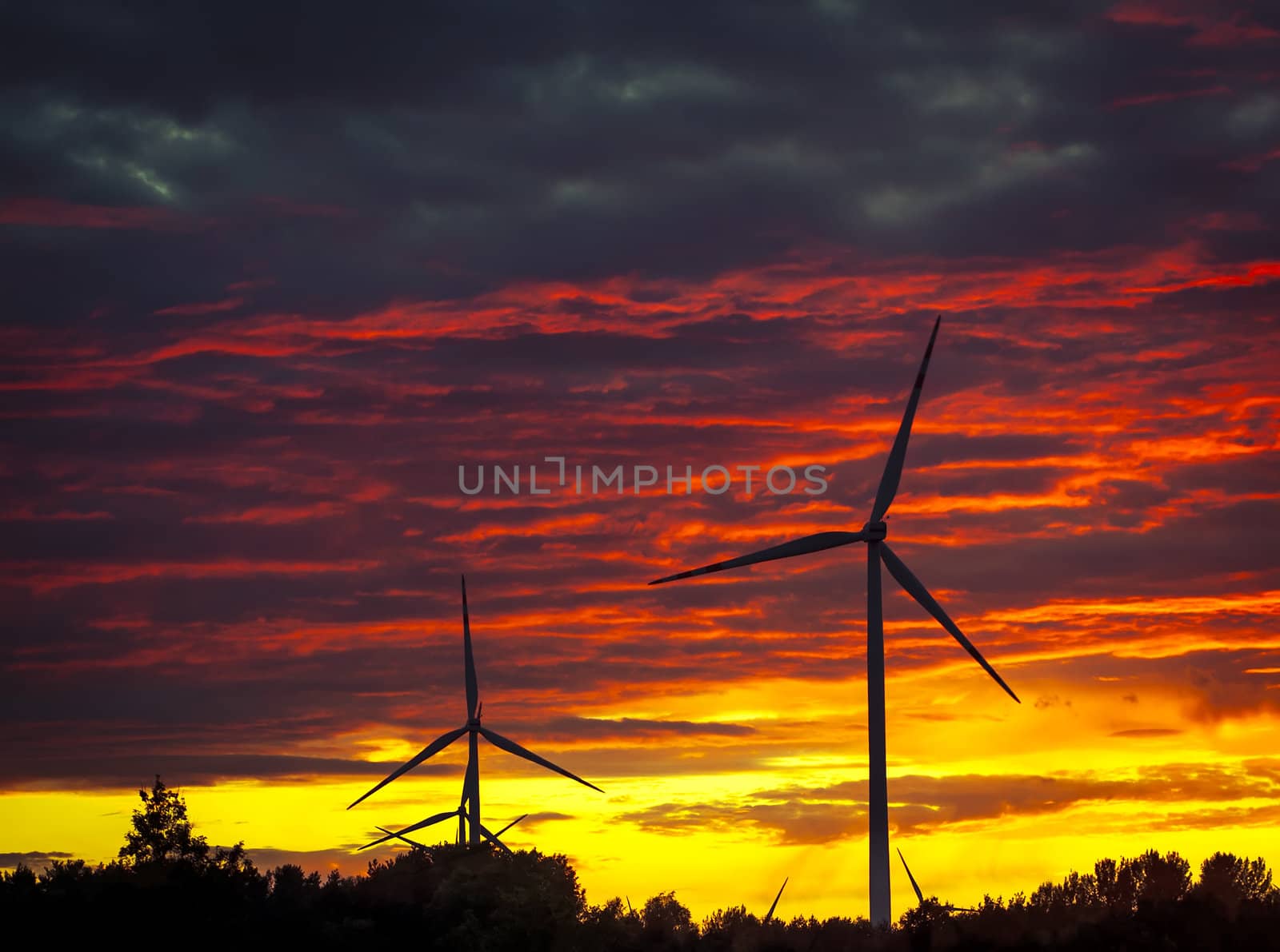 A silhouette of windturbines on a amazing sunset
