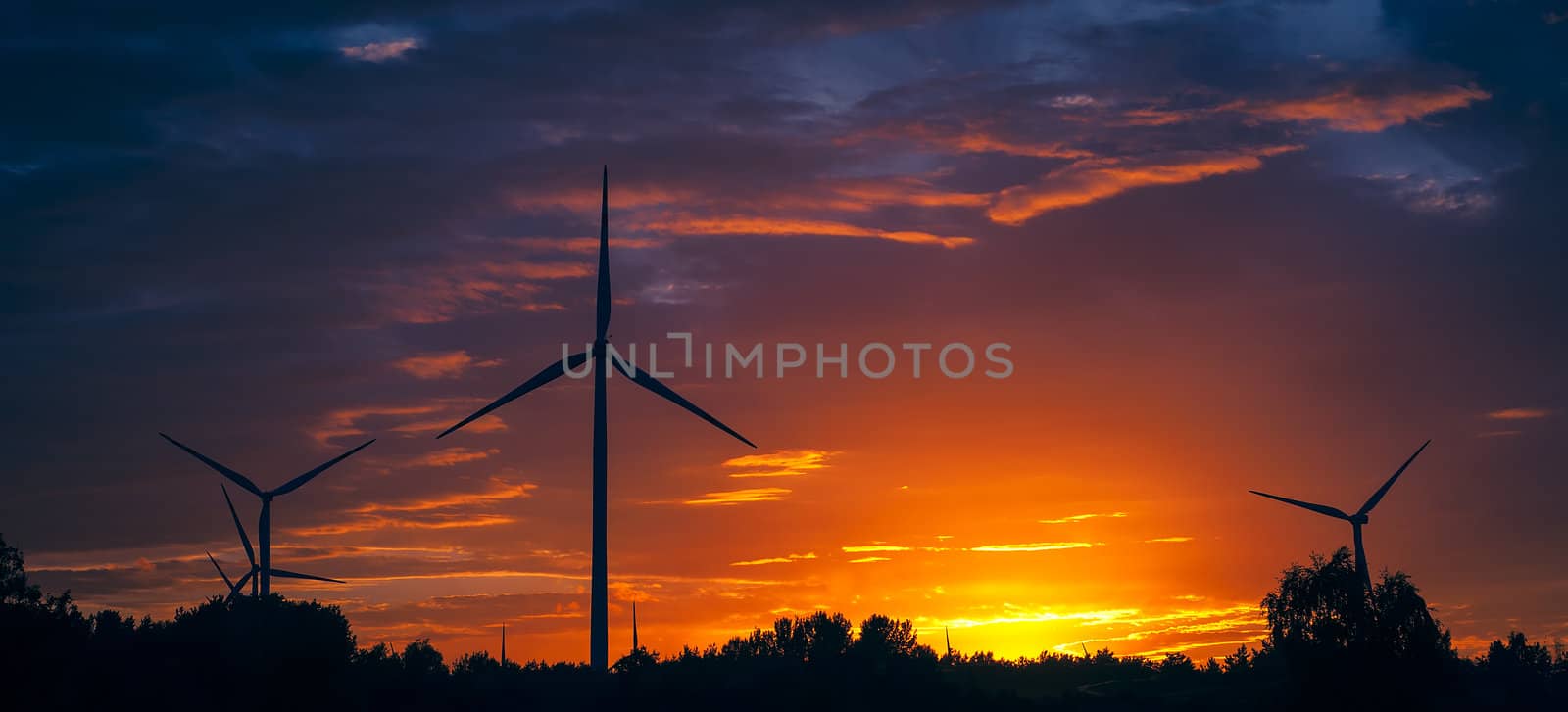 A silhouette of windturbines on a amazing sunset