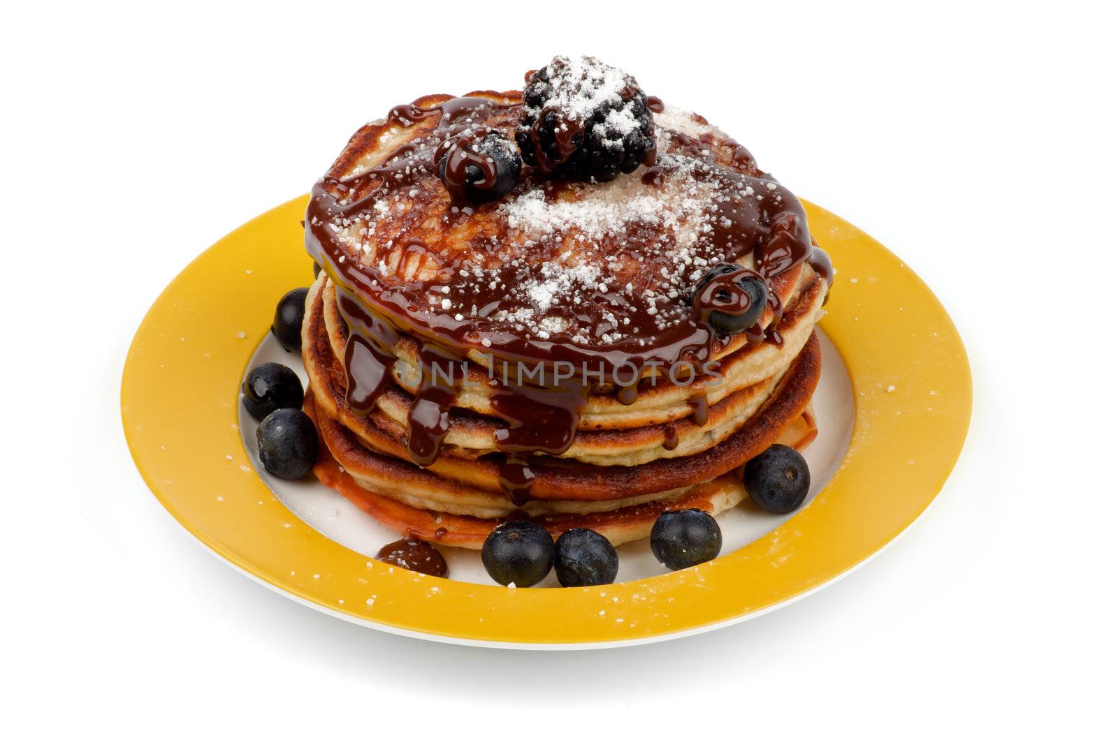 Stack of Delicious Pancakes with Blackberries, Blueberries, Chocolate Glaze and Sugar Powder on Yellow Plate isolated on white background