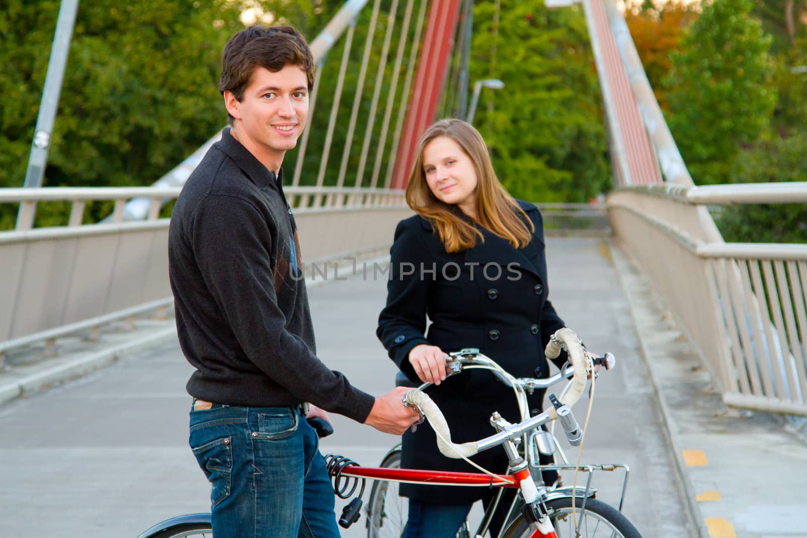 A married man and woman with their bikes on a bicycle path bridge.