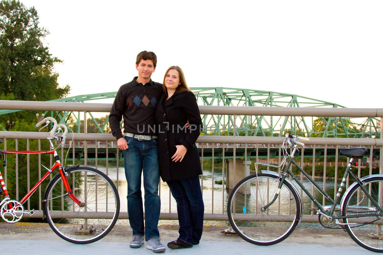 A married man and woman with their bikes on a bicycle path bridge.