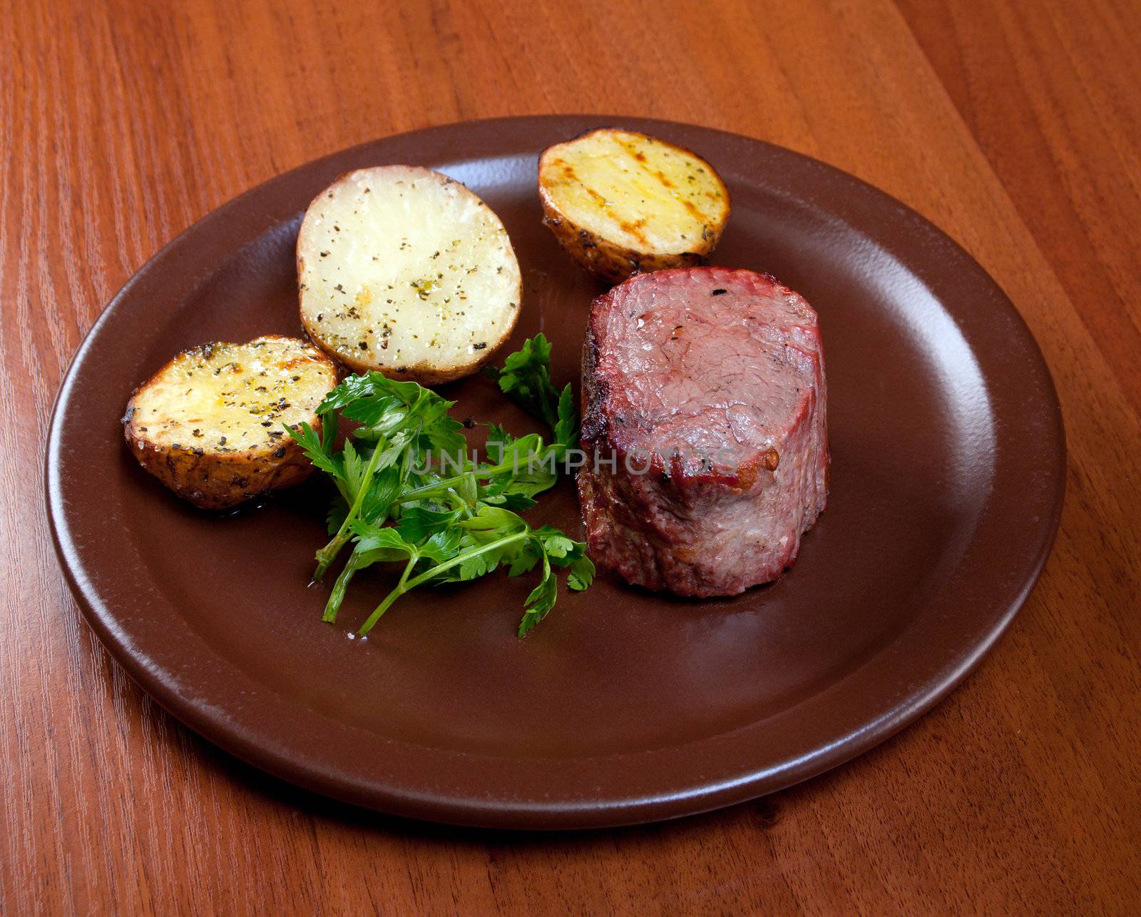 Grilled beef on white plate with potatoes salad and tomatoes 
