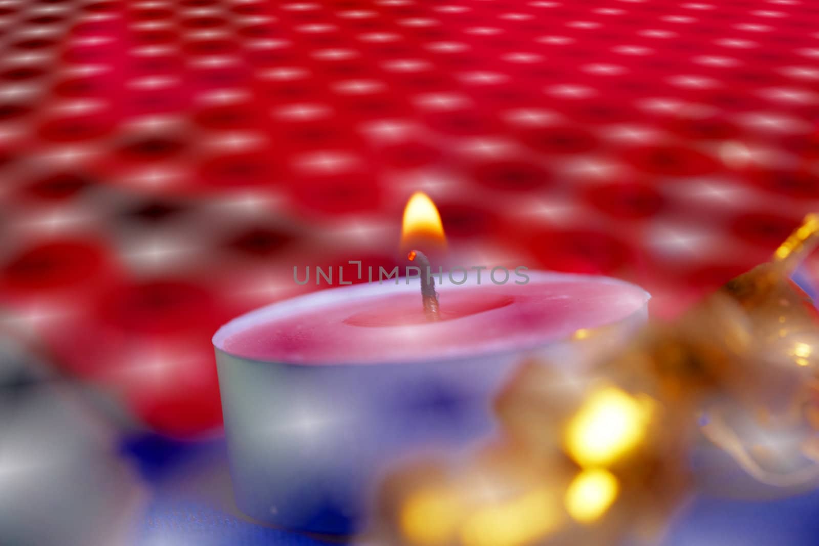Burning candle and red flowers on a table