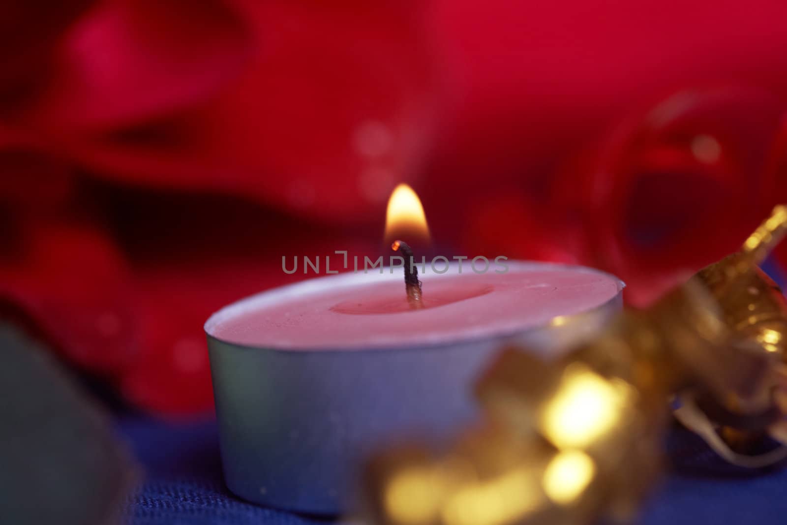 Burning candle and red flowers on a table