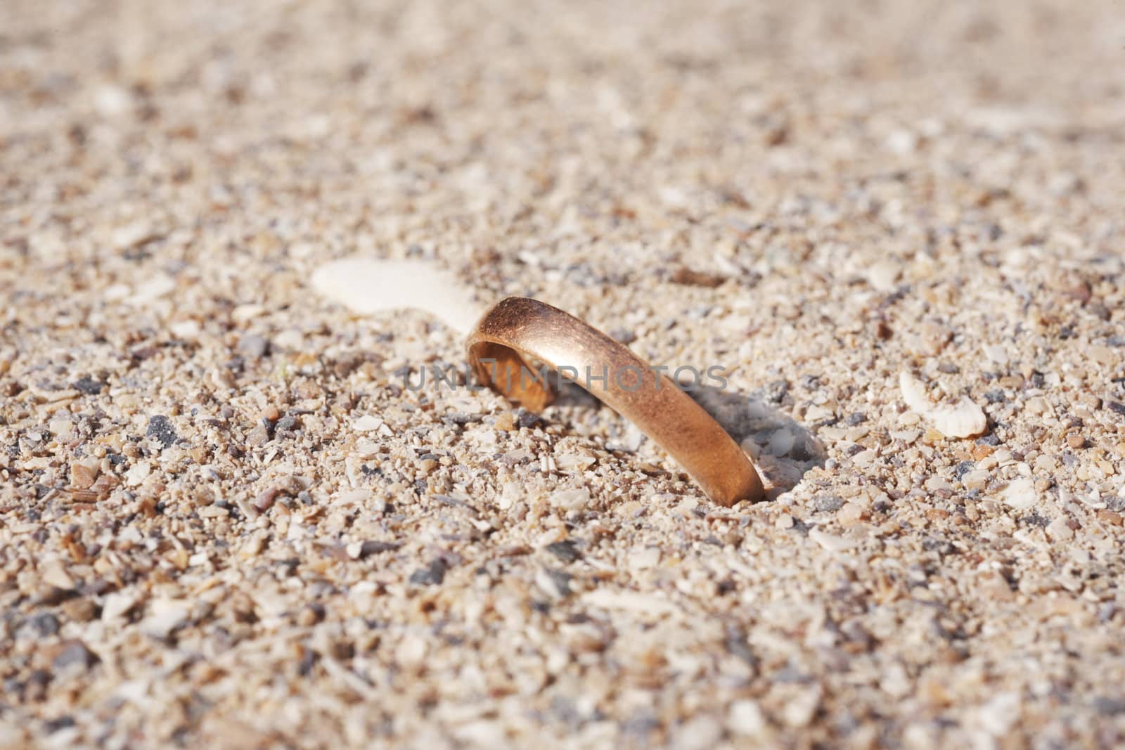 The gold wedding ring lays on sea sand