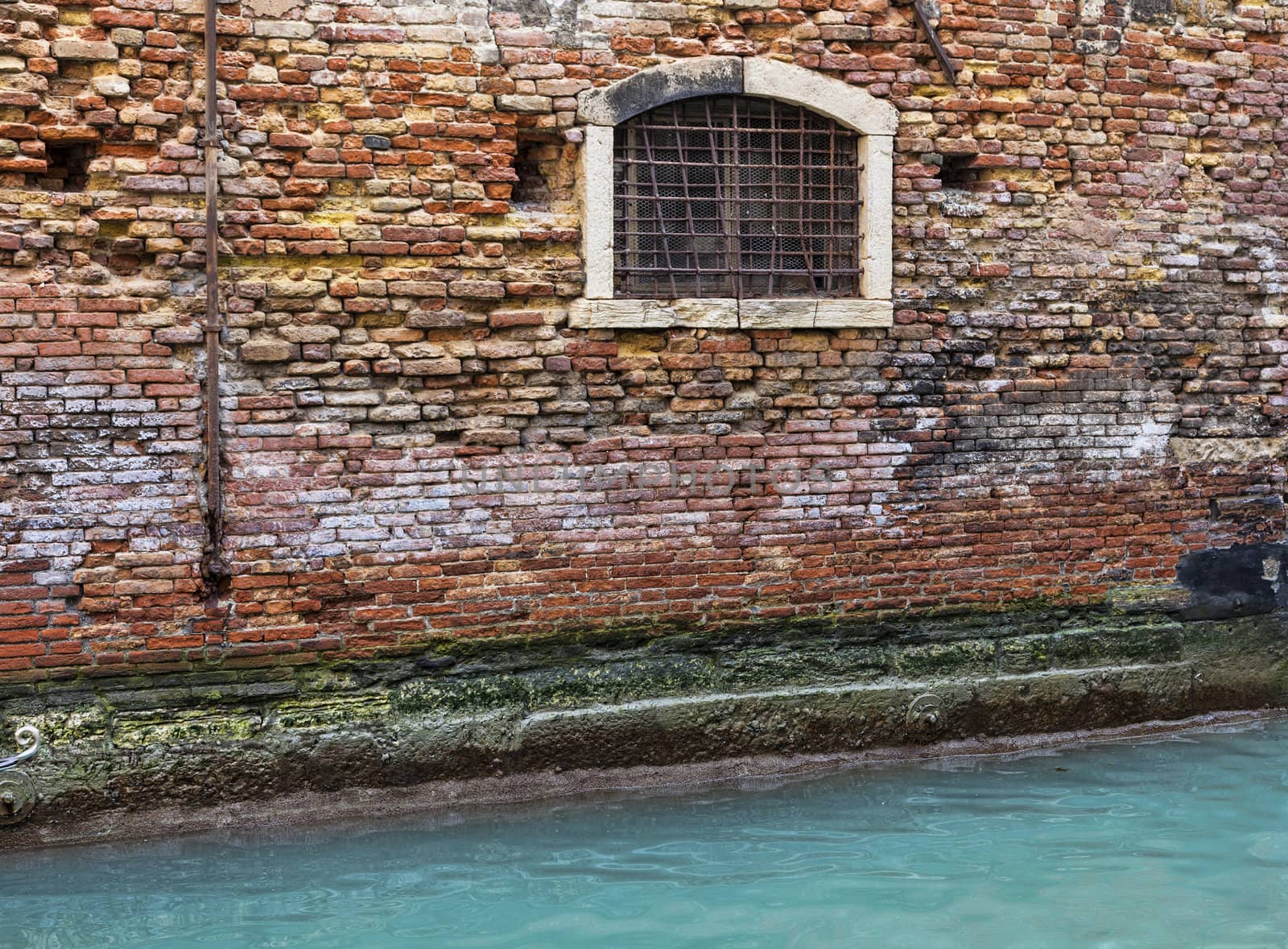 Detail of a brick wall of a Venetian house near a specific canal.
