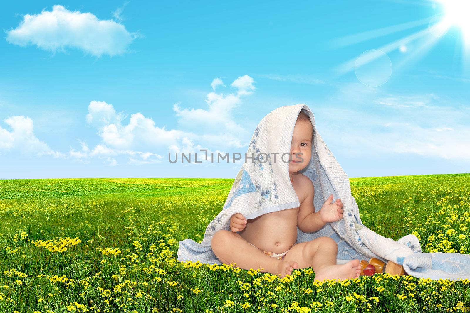 Beautiful baby looking out from under towel on a green background. Summer